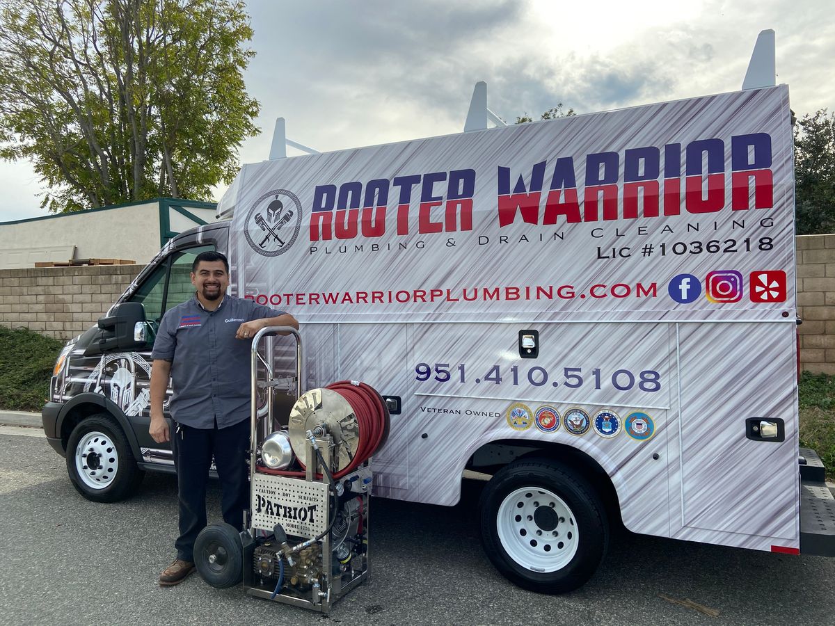 Guillermo of Rooter Warrior Plumbing standing with the Patriot jetter beside a branded service truck